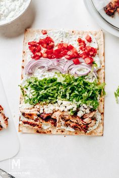 a flatbread topped with meat and veggies on top of a cutting board