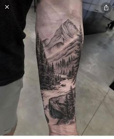 a man's arm with a mountain scene tattoo on the left side of his arm