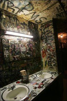 a bathroom with graffiti all over the walls and two sinks in front of a mirror