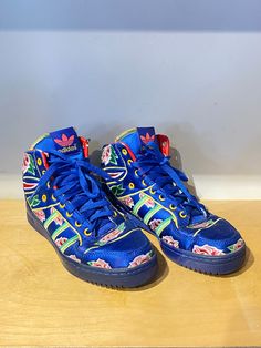 Adidas x Jeremy Scott Blue Floral High Tops! These eye catching sneakers feature a blue satin base with colorful embroidered flowers throughout. They are marked a Men's Size 7.5 and are in overall excellent condition with minor wear to the leather at the ankle, priced as is. Approx. Measurements: Width: 3.5" Heel to toe: 10" Blue Sporty High-top Sneakers For Spring, Sporty Blue High-top Sneakers For Spring, Blue Lace-up High-top Sneakers For Spring, Blue High-top Sneakers With Round Toe For Spring, Blue High-top Sneakers For Spring, Spring Blue High-top Sneakers With Rubber Sole, Sporty Floral Print Sneakers For Streetwear, Floral Print High-top Sneakers For Streetwear, Blue Sneakers With Boost Midsole For Spring