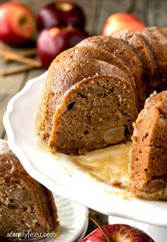 a bundt cake on a plate with an apple in the background and sliced apples