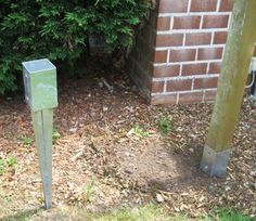 two metal poles in front of a brick wall and green grass next to a sidewalk