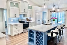 a kitchen with white cabinets and blue island