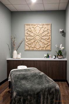 a spa room with a large wooden sculpture on the wall and a massage table in front of it