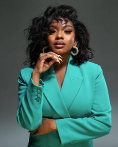 a woman in a green suit posing for the camera with her hand on her chin