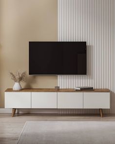 a flat screen tv mounted to the side of a white cabinet in a living room