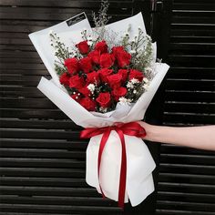 a person holding a bouquet of red roses