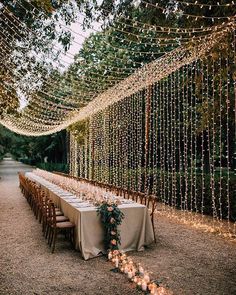 a long table is set up with candles and greenery for an outdoor wedding reception