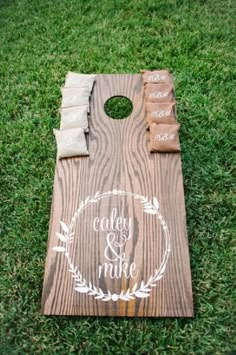 a cornhole board with chalk writing on it sitting in the grass next to some chips