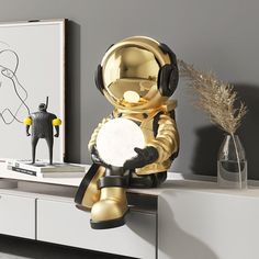 an astronaut figurine sitting on top of a white dresser next to a vase