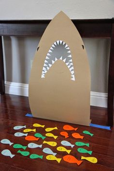 a paper cut out of a shark's mouth with fish on the floor next to it