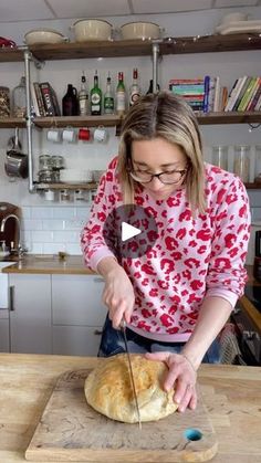 a woman cutting bread on top of a wooden table