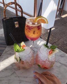 two cocktails are sitting on a marble table