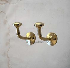 two brass colored hooks on a white wall