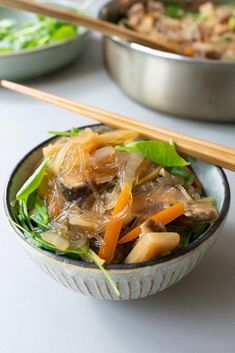 a close up of a bowl of food with chopsticks on the table next to it