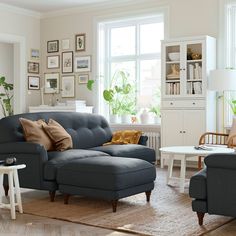 a living room with blue couches and white tables in the corner, along with pictures on the wall