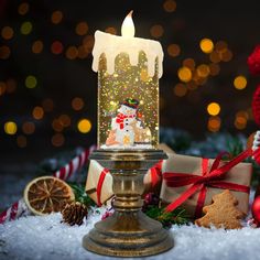 a lit candle sitting on top of a table next to christmas decorations and presents in front of a tree