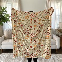 a woman is holding up a blanket in her living room