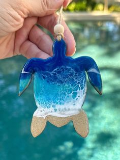 a hand holding a glass ornament shaped like a turtle in blue and white