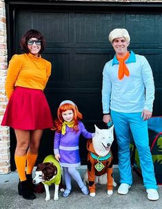 three people in costumes standing next to two dogs and a man with glasses on his head