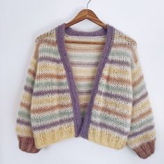 a multicolored sweater hanging on a wooden hanger