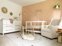 a baby's room with a crib, chair, dresser and mirror on the wall