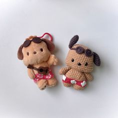 two small stuffed animals sitting next to each other on a white surface with one holding a string