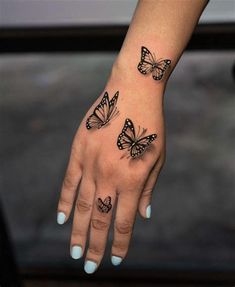 a woman's hand with three butterfly tattoos on her left wrist and the other arm