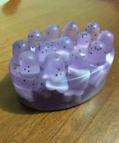 a bowl filled with lots of little purple candies on top of a wooden table