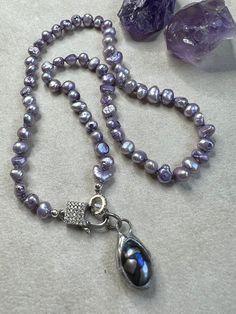 "16\" long of hand knotted, light purple, freshwater potato pearls. So sweet. They are knotted on purple nylon and come together at the CZ lobster clasp. The removable pendant is a hand soldered peacock pearl. You can also add your own charms and pendant. This is such a great layering piece. All of my pieces are created with great care, quality elements and attention to detail. I hope you are happy with your purchase and should you have any concerns or questions, please let me know. I am happy to help. Every item is handmade so please use care when wearing and storing. Please avoid wearing in the water and using oils, lotion and any chemicals so the quality of the stones and metals can be best protected. All items will be sent in a linen gift bag and packed securely. If you have any questi Purple Pearl Single Strand Jewelry, Purple Single Strand Pearl Jewelry, Adjustable Purple Pearl Necklace, Purple Single Strand Pearl Necklace, Peacock Pearl, Handmade Market, So Sweet, Layering Pieces, Light Purple