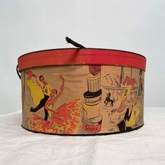 an old fashioned tin can with cartoon pictures on it's side and a tassel hanging from the top