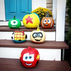 four pumpkins painted to look like cartoon characters sitting on the front steps of a house