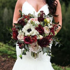 a bride holding a bouquet of red and white flowers