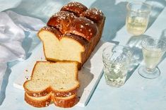 a loaf of bread sitting on top of a white cutting board next to some glasses