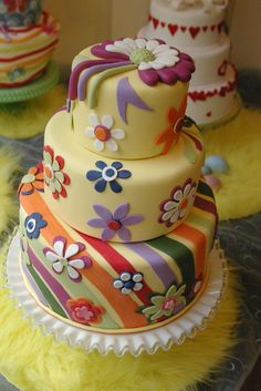 three tiered multi - layer cake with flowers and hearts on top, surrounded by yellow fur