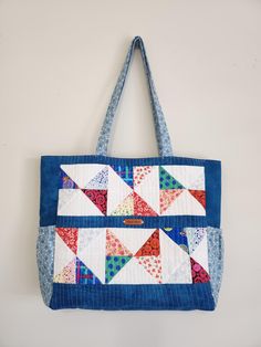 It was so much fun making this quilted tote with a rainbow of charm pack colors for the square triangles, cotton fabrics, fusible woven interfacing, fusible fleece, top magnetic snap, one interior zippered pocket and two slip pockets, two external pockets on the side panels, and shoulder straps. Dimensions: 18" x 15" x 4 1/2" (side) x 4" (bottom). Patchwork Tote Bags, Quilted Totes, Charm Pack, Panel Siding, Cotton Fabric, Blue And White, Tote Bag, Blue, Fabric