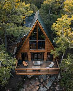 an aerial view of a log cabin surrounded by trees and rocks, with the roof covered in shingles