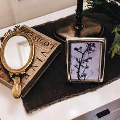 a small mirror sitting on top of a table next to a candle and some plants