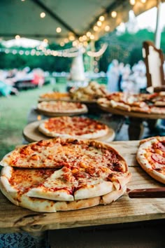 several pizzas sitting on wooden platters under a tent