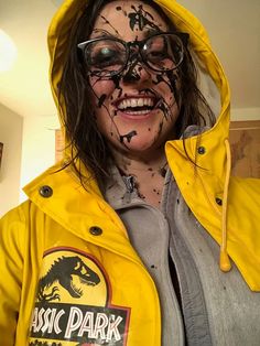 a woman in yellow jacket and glasses with black paint on her face