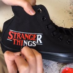 Plain black high top converse hand painted with the Stranger Things logo and Eleven design. #strangerthings #eleven #converse #sneakers #timelapse #painting #handpainted #paintedshoes #shoes #chucks #milliebobbybrown Stranger Things Converse, 80s Converse, Stranger Things Logo, Converse Aesthetic, Stranger Things Eleven, Converse Outfit, Black High Top Converse, Custom Painted Shoes