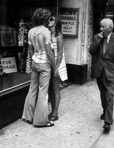 an old photo of two people walking down the street talking on their cell phones,