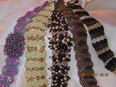 several bracelets are lined up together on a white cloth with gold and silver beads