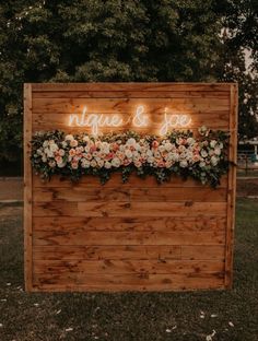 a wooden sign with flowers on it that says unique and joy written in neon lights