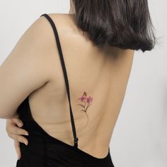 the back of a woman's shoulder with a pink flower tattoo on her left side