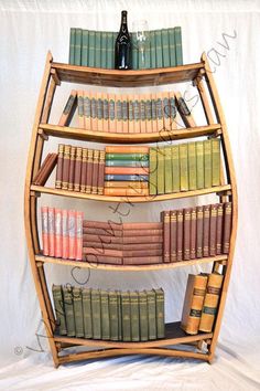 a wooden book shelf filled with books next to a bottle of wine on top of a white sheet