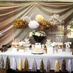 a table topped with lots of desserts next to a white table cloth covered wall