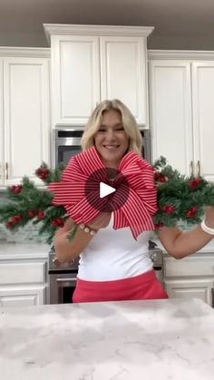 a woman is holding up some christmas wreaths