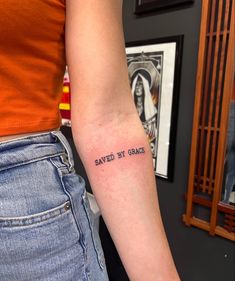 a woman's arm with the words saved by grace tattooed on her left arm