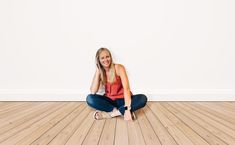 a woman sitting on the floor with her legs crossed in front of her face and smiling